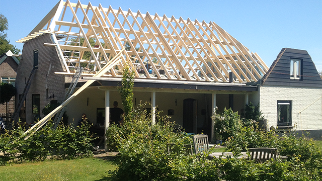 renovatie van een dak van een witte boerderij in Elspeet. Door de sporenkap kun je van binnenshuis de balken van het dak nog zien.