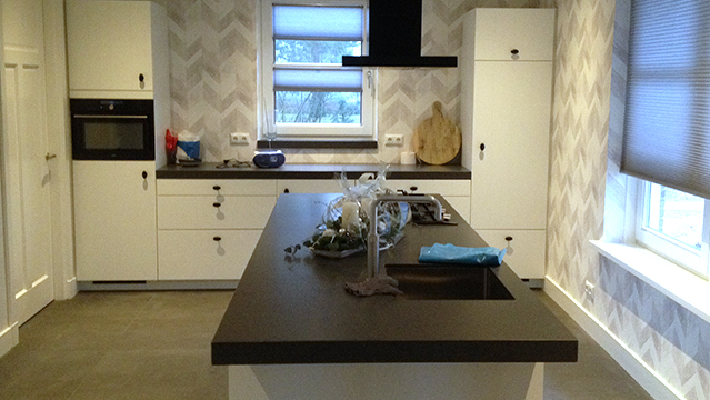 Witte keuken inbouw apparatuur en een kookeiland met donker blad.