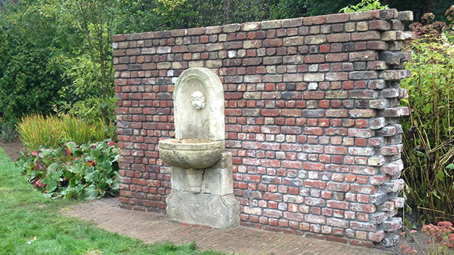 Tuinmuur met antieke witte fontein