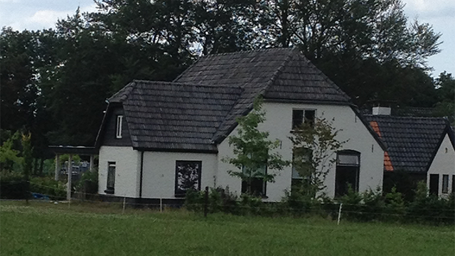 De woning voor de renovatie van het dak renovatie van een dak van een witte boerderij in Elspeet. Door de sporenkap kun je van binnenshuis de balken van het dak nog zien.