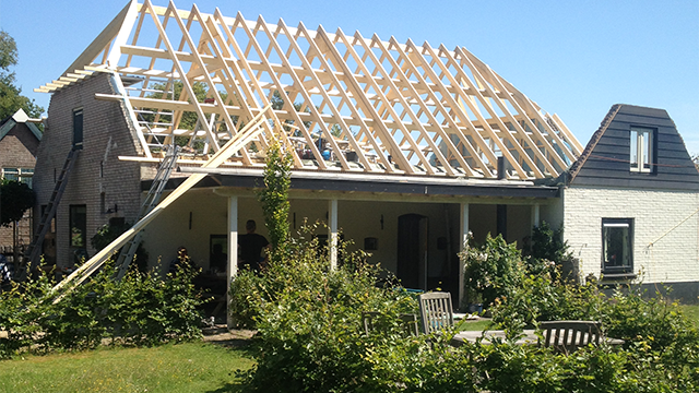 De woning tijdens de renovatie van het dak. De sporenkap is hier goed zichtbaar renovatie van een dak van een witte boerderij in Elspeet. Door de sporenkap kun je van binnenshuis de balken van het dak nog zien.