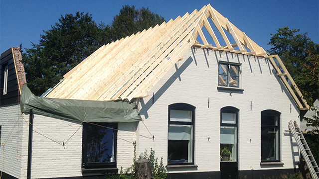 De woning tijdens de renovatie van het dak. De sporenkap is hier goed zichtbaar renovatie van een dak van een witte boerderij in Elspeet. Door de sporenkap kun je van binnenshuis de balken van het dak nog zien.