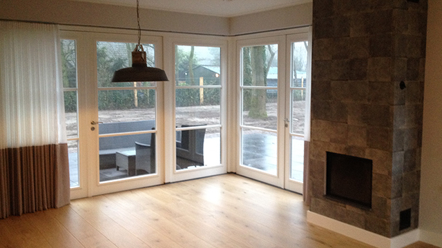 Interieur woonkamer met open haard en uitzicht op de tuin. Van den Berg, Bouwveluwe Interieur woonkamer met open haard en uitzicht op de tuin.